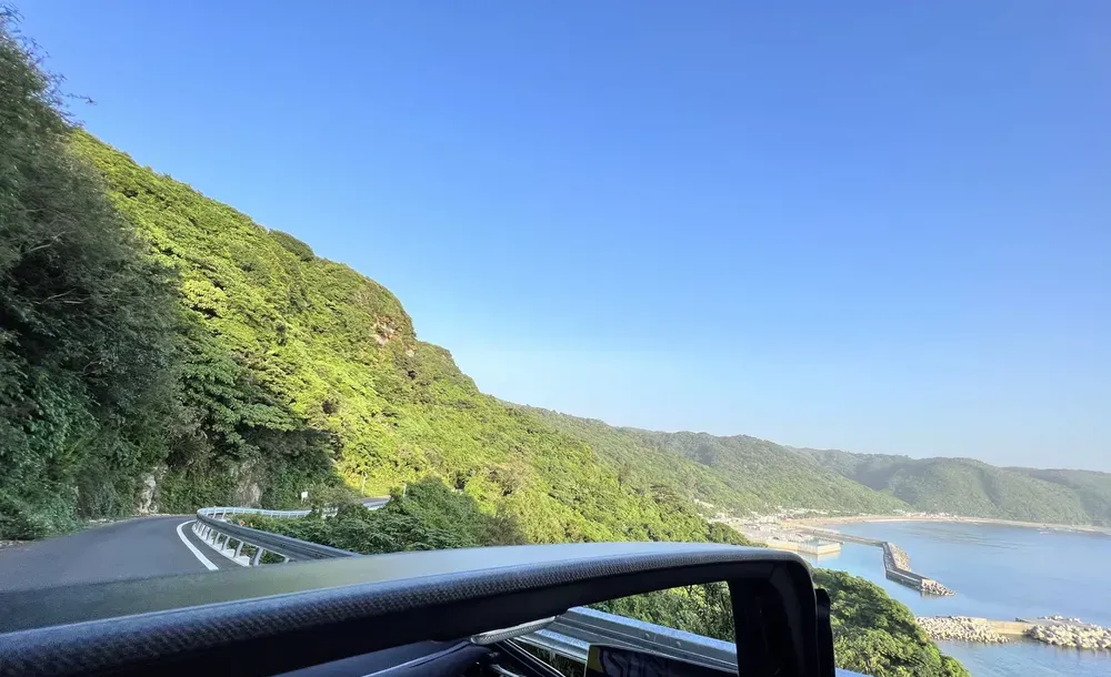 幌を開けたシティ カブリオレから見た沖縄の海沿いの道