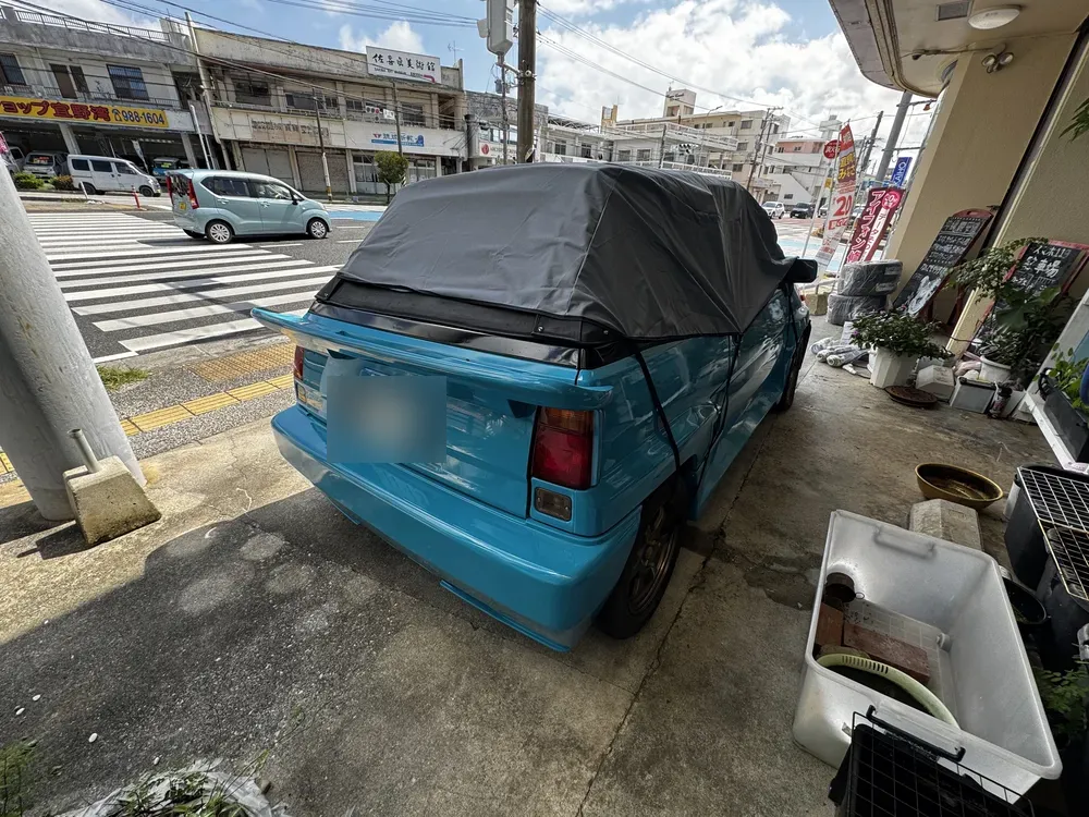 幌にカバーを掛けて店の前で出発を待つマイアミブルーのシティ カブリオレ