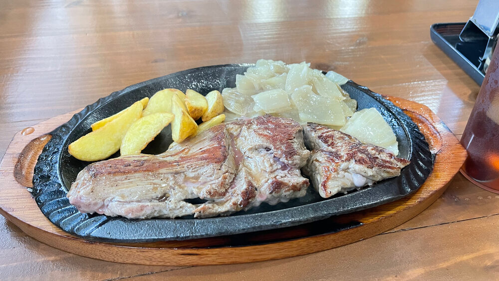 鉄板に載ったステーキとつけ合わせ