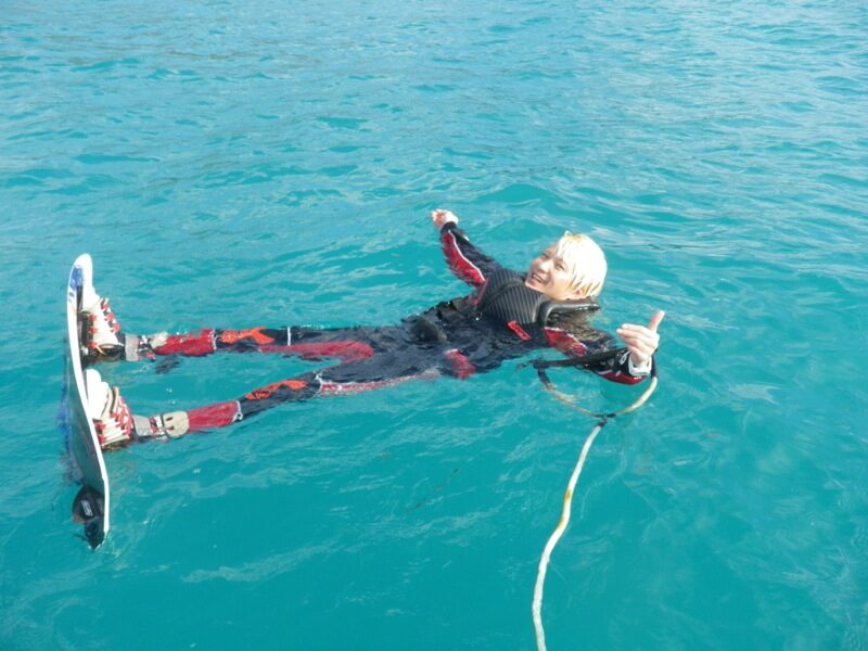 青い海にボードと一緒に浮かぶ富村浩樹