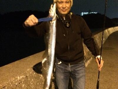 夜の堤防で釣り上げた太刀魚を持つ富村浩樹
