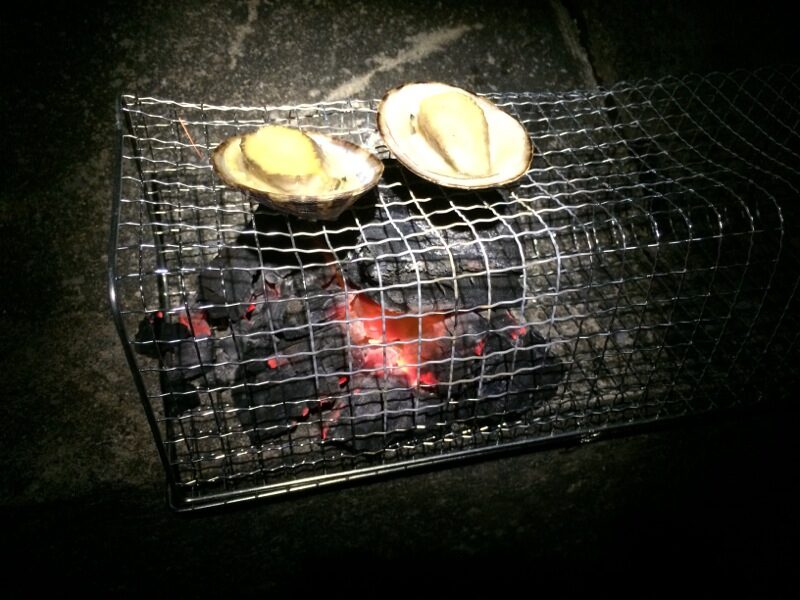 夜の炭火の網の上で焼ける貝